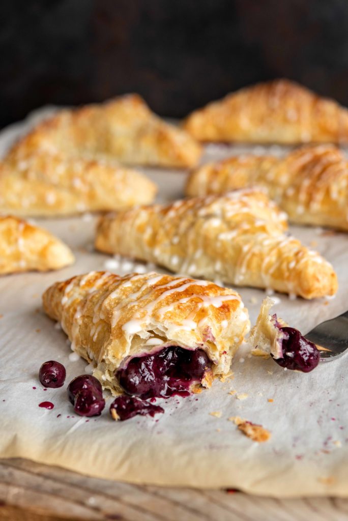 Fresh baked blueberry turnovers lined up on a baking sheet