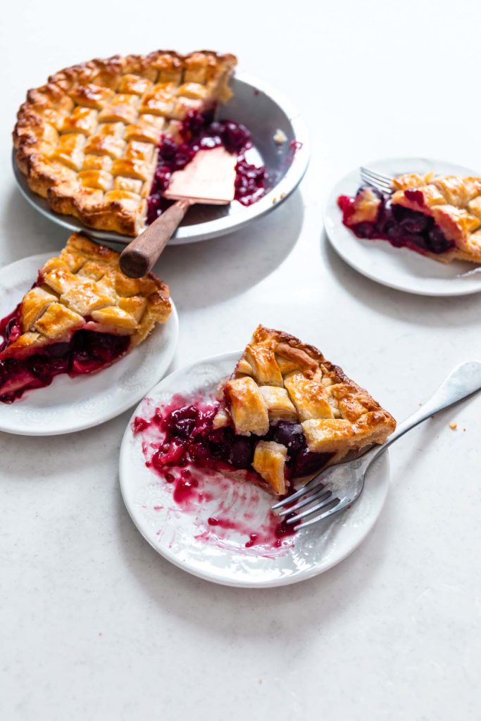 three warm slices of dark sweet cherry pie with flakey pastry crust